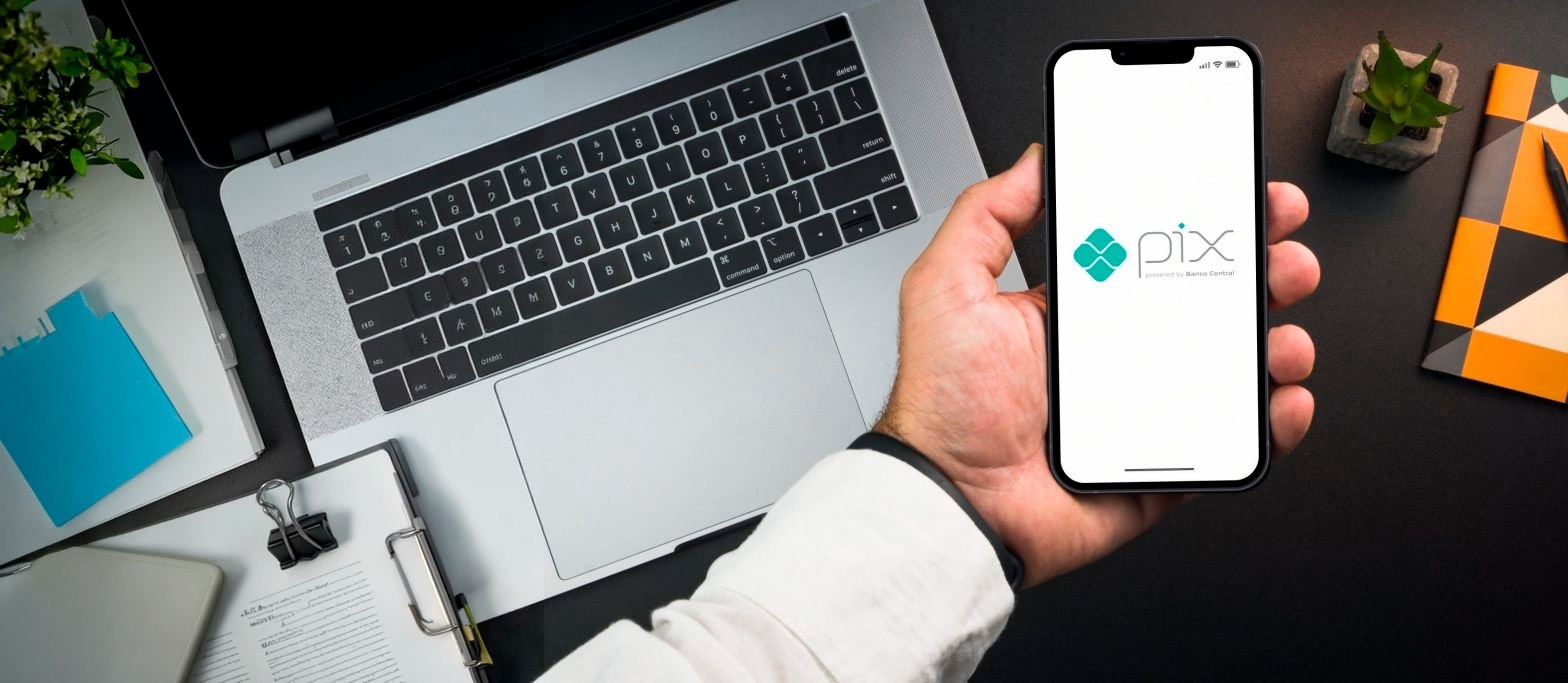 Pagamento Pix sendo realizado em um smartphone ao lado de um notebook