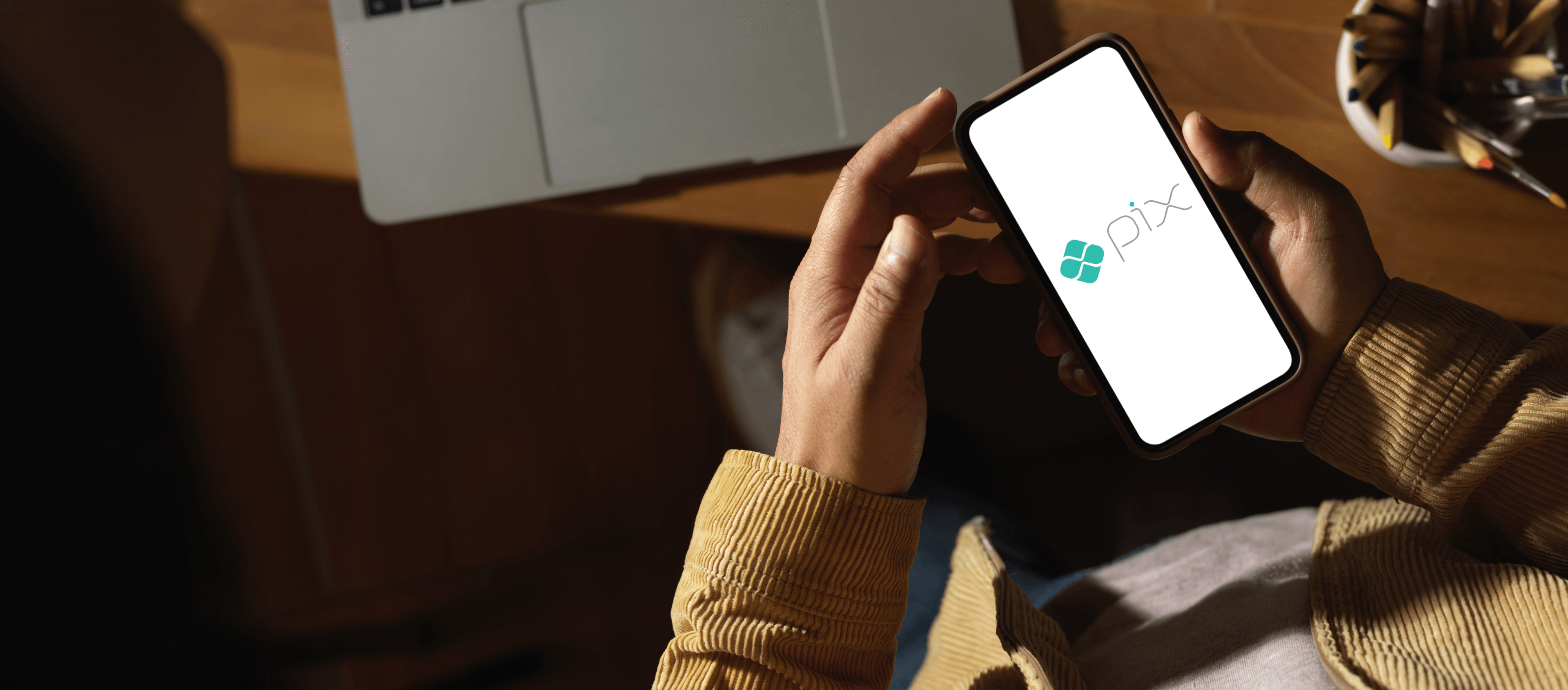 Pagamento Pix sendo realizado em um smartphone ao lado de um notebook